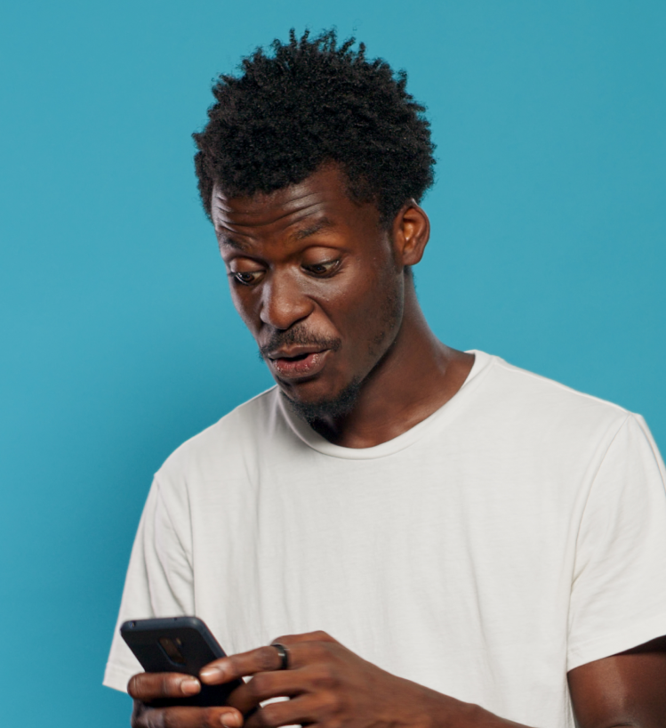 Surprised young man in a white t-shirt using smartphone against a blue background — representing user interaction and real-time engagement in digital marketing.